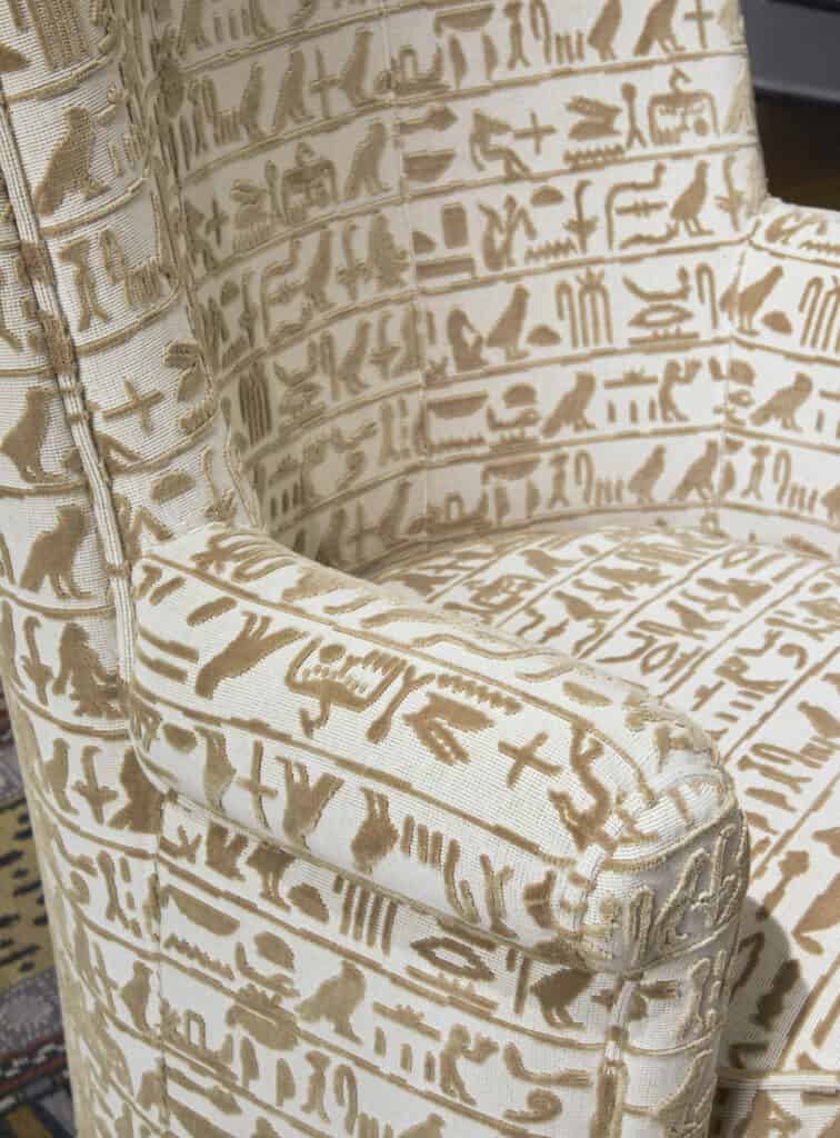Close up image of armchair covered in hieroglyphic inspired fabric by Pierre Frey