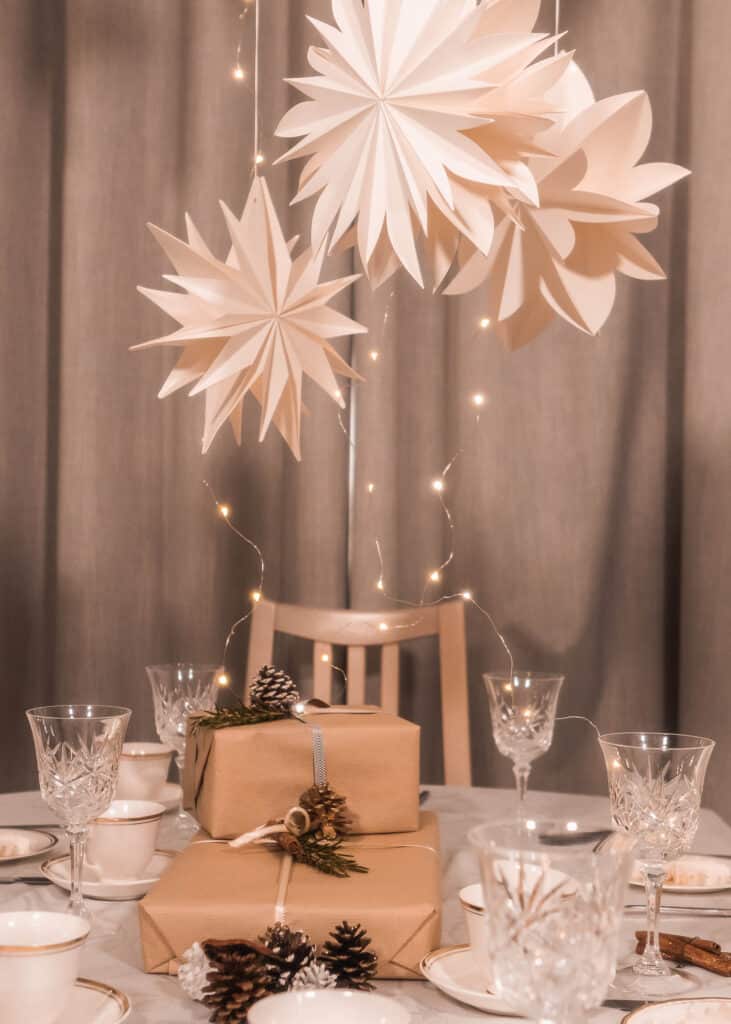 Paper snowflake decorations hung over dining table laid for dinnner