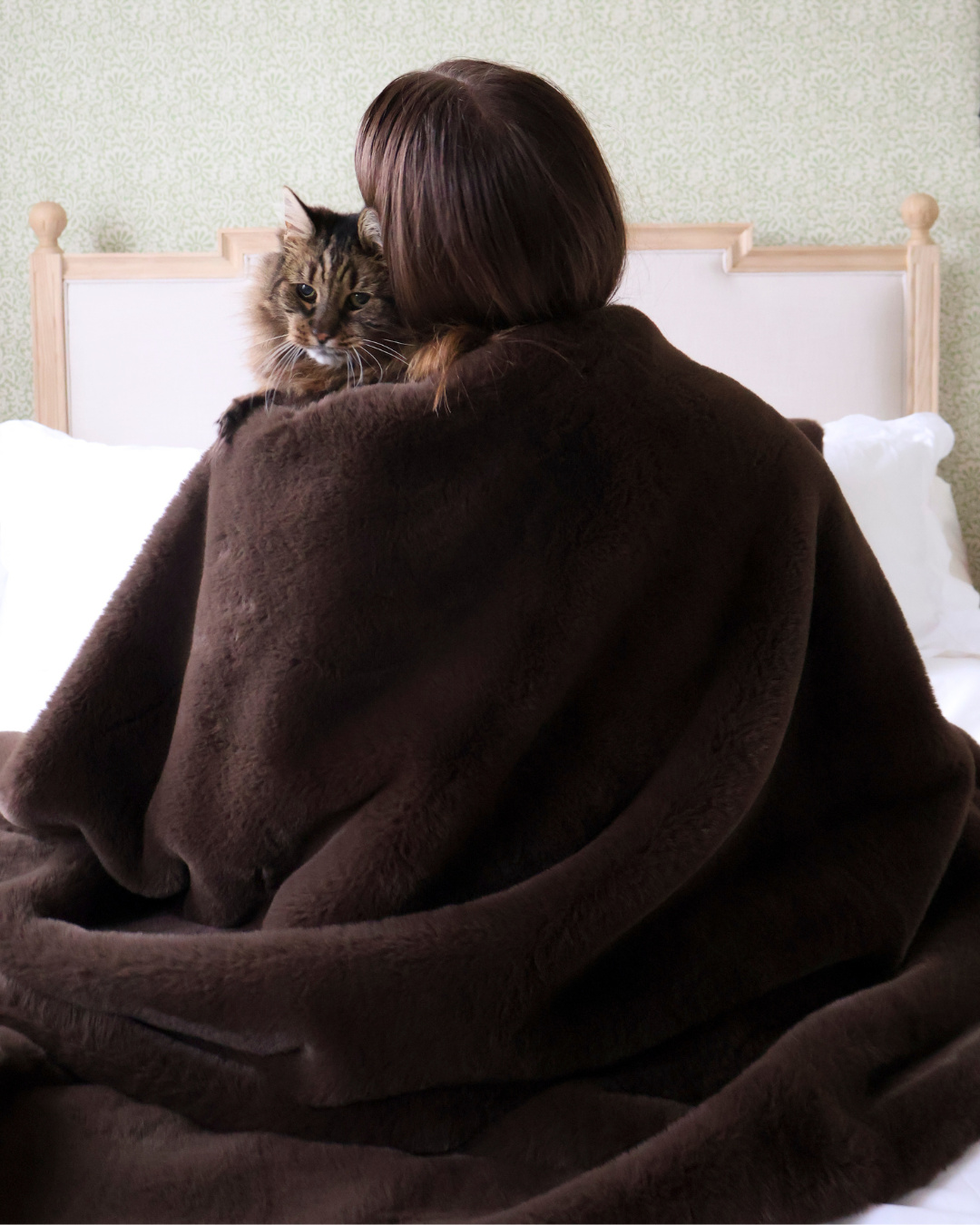 he back of a woman wrapped in a large blanket with a child on her shoulder.